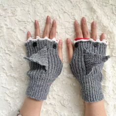 a woman's hands wearing gray knitted mitts with an elephant on them