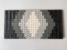 a piece of art made out of black and white squares on a wall with a light shining through the middle