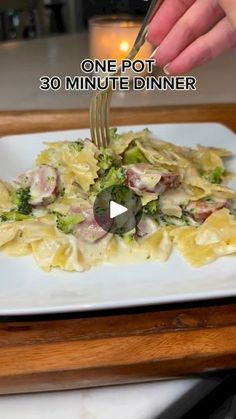 a person is cutting into a plate of pasta with broccoli and meat on it