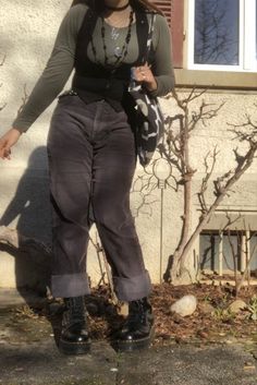 A mid-size person/girl wearing a blck tight waistcoat with a tight sage green long sleeve underneath, vintage black jeans, platform dr. Marten shoes and multiple crystal rings and bracelets. The person is also wearing multiple silver necklaces, one in form of a fairy, another in form of a moon, one in form of a butterfly, a thrifted black bead necklace and a green crystal bead necklace. Dark 80s Aesthetic Clothes, Plus Size Representation, Bruno Major Concert Outfit, Black Coudroy Pants Outfit Women, Winter Dark Aesthetic Outfits, Dark Earth Tones Outfit, Whimsigoth Aesthetic Clothes, Dark Earth Tone Outfits, Mid Size Doc Martens Outfit