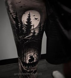 a man's leg with a black and white tattoo on it that has an image of a deer in the woods at night