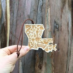 a hand holding a piece of wood that has been carved into the shape of a state