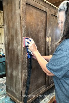 a woman is using a steam mop to clean an old cabinet door with the help of a power washer