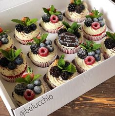 a box filled with cupcakes covered in frosting and topped with fresh berries