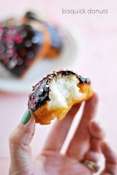 a hand holding a half eaten donut with chocolate sprinkles on it