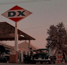 an old gas station with cars parked in front of it and a sign that says dx