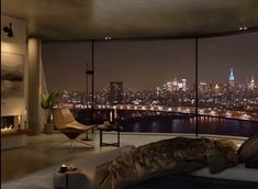 a living room filled with furniture next to a large window overlooking a city at night