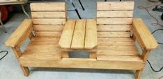 two wooden chairs sitting next to each other on top of a cement floor in a room