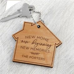 a wooden keychain with a new home and beginning new memories engraved on it