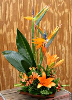 an arrangement of tropical flowers on a wooden table