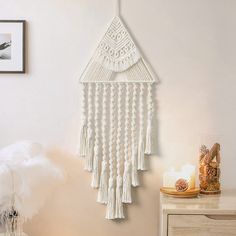 a white wall hanging with tassels on it in a room next to a dresser