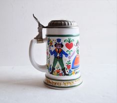 a beer mug with a wrench stuck in it's handle that is decorated with flowers and hearts