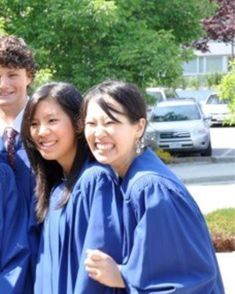 four people in blue graduation gowns posing for a photo