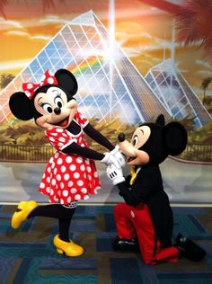 mickey and minnie dancing together in front of a mural