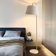 a bed room with a neatly made bed and a large lamp on the side table