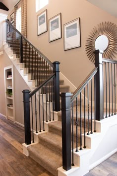 a staircase with black railings and pictures on the wall