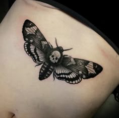 a black and white butterfly tattoo on the back of a woman's stomach