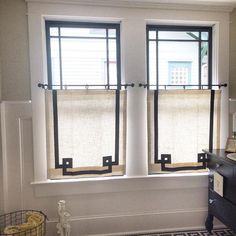 two windows with roman shades in a bathroom next to a rug and sink area on the floor