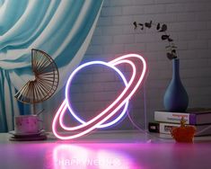 a neon sign with the saturn symbol on it next to a vase and some books