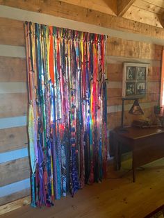 there are many colorful ribbons hanging on the wall in front of a piano and window