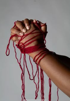 a woman's arm wrapped in red string with her hand on top of it