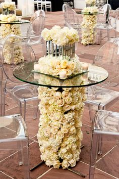 there are many clear chairs and tables with flowers on them in the centerpieces