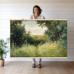 a woman holding up a painting in front of her face and smiling at the camera