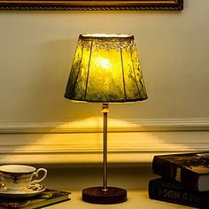 a lamp that is on top of a table next to some books and a cup