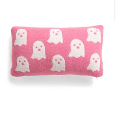 a pink and white pillow with ghost faces on the front, sitting in front of a white background