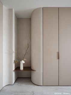 a white vase sitting on top of a wooden shelf next to a beige cabinet and shelves