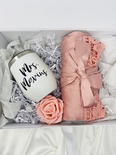 a pink and white gift box containing a coffee mug, mittens, and rose