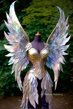 a mannequin with wings on it in front of some trees and bushes at night