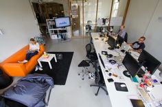 people sitting at desks in an office with computers and laptops on the tables