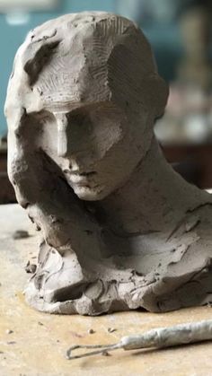 a clay sculpture of a woman's head on a workbench with a pair of scissors