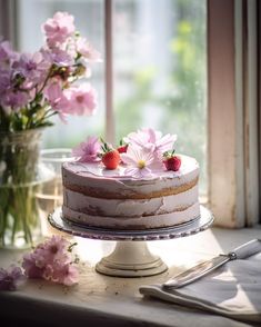 a cake sitting on top of a table next to pink flowers and a glass vase