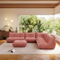 a large pink couch sitting on top of a hard wood floor next to a window