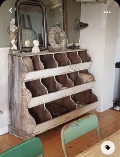 an old wooden shelf with several storage bins on it and two green chairs in front of it