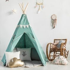 a teepee tent sitting on top of a white floor next to pillows and toys