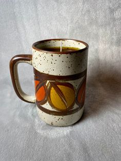 a coffee cup that is sitting on a white table cloth with a candle in it