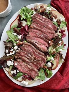 a white plate topped with meat and salad next to a cup of coffee on top of a table