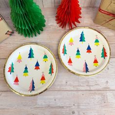 two paper plates decorated with christmas trees on them next to some gift boxes and decorations