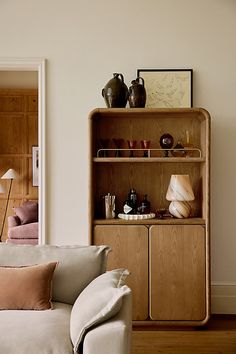 a living room with a white couch and wooden shelves filled with vases on top of them