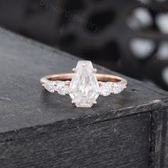 a white diamond ring with three diamonds on it's side, sitting on top of a wooden box