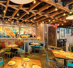 the inside of a restaurant with wooden tables and chairs, colorful artwork on the wall