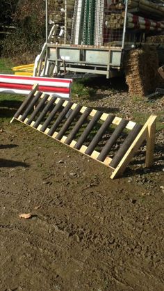 a wooden slat laying on the ground in front of a tractor trailer and hay bales