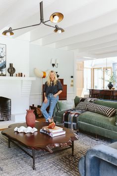 a woman sitting on top of a coffee table in a living room next to a fire place