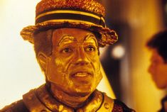 a close up of a statue of a man wearing a top hat and gold paint