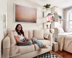 a woman sitting on top of a couch next to a bed