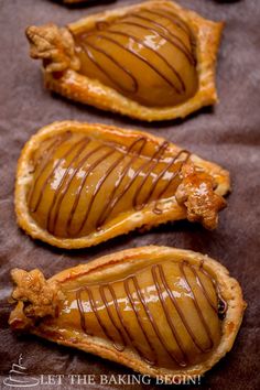 three pieces of pastry with caramel drizzled on them sitting on a baking sheet