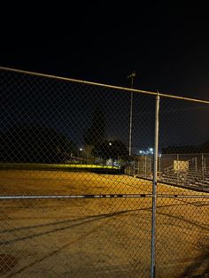 an empty baseball field at night with the lights on and no one in it,